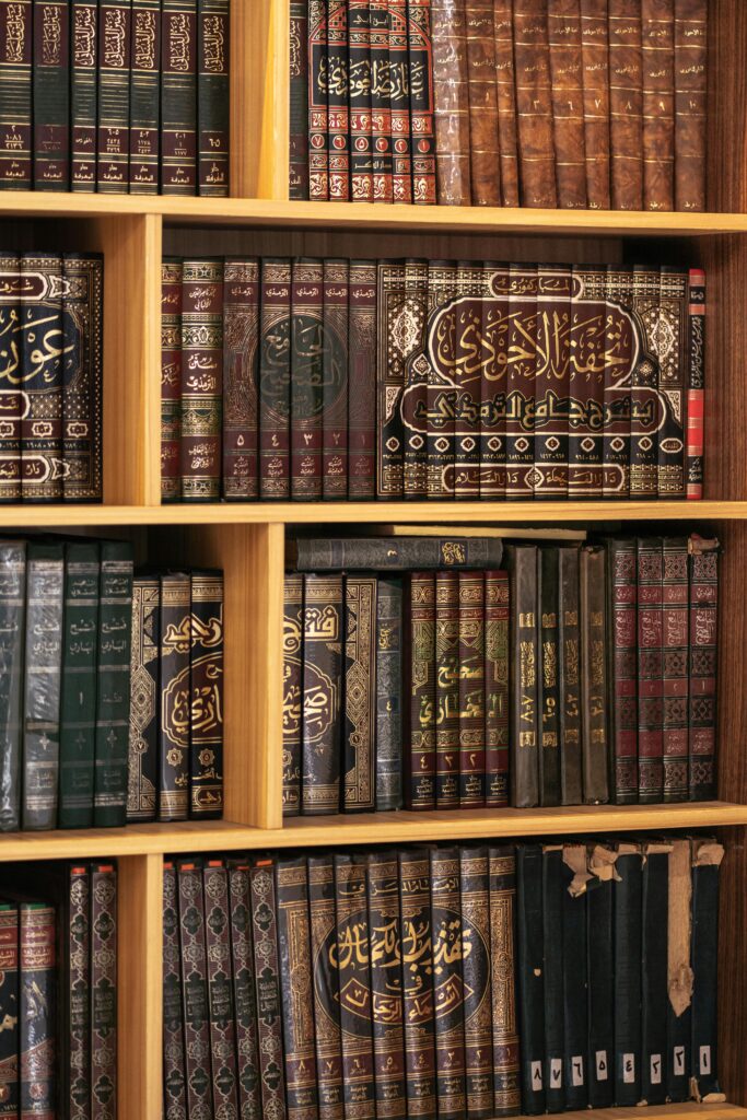 A detailed view of a bookshelf filled with ornate Islamic texts, showcasing intricate Arabic calligraphy.